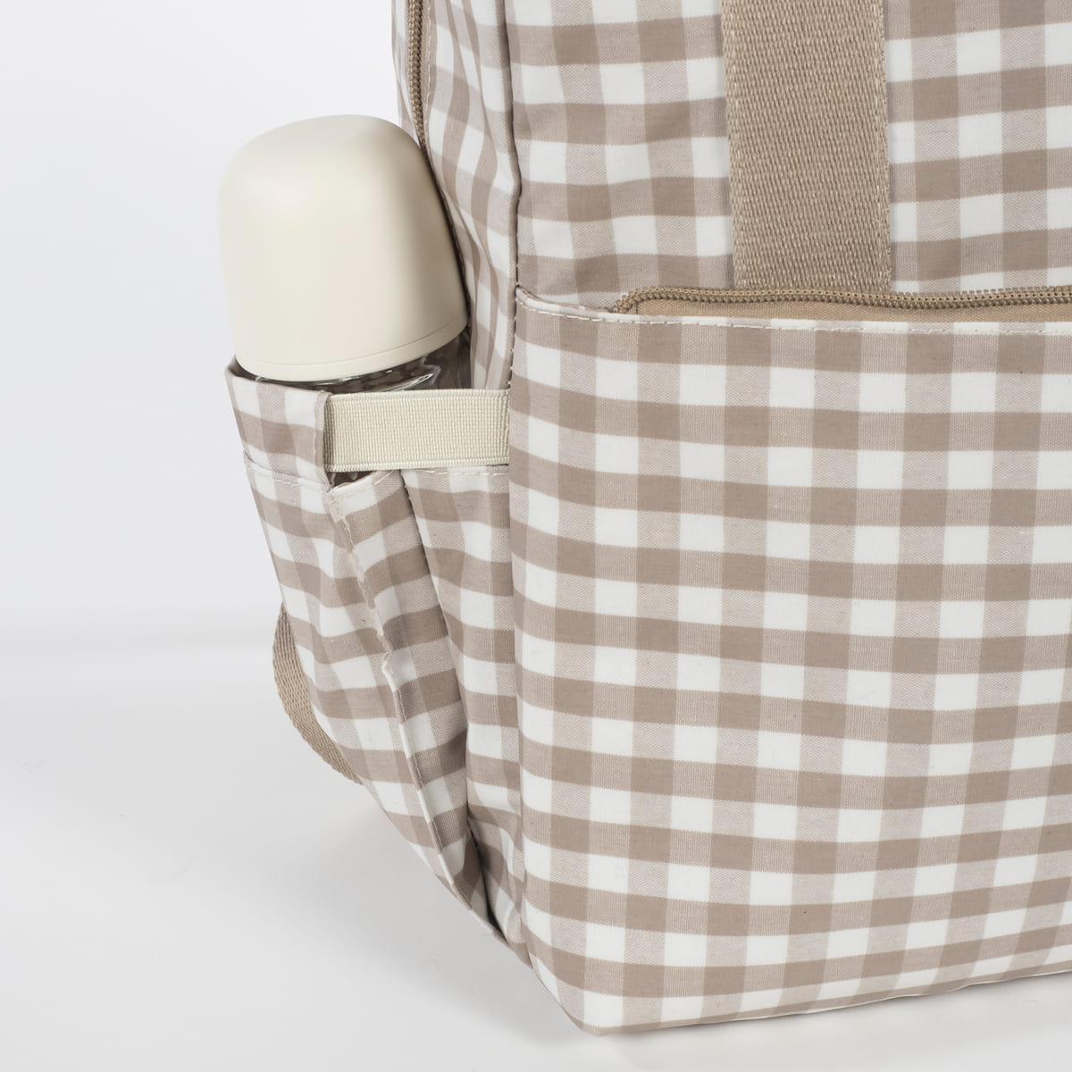 Mochila bege e branca xadrez com garrafa no bolso lateral