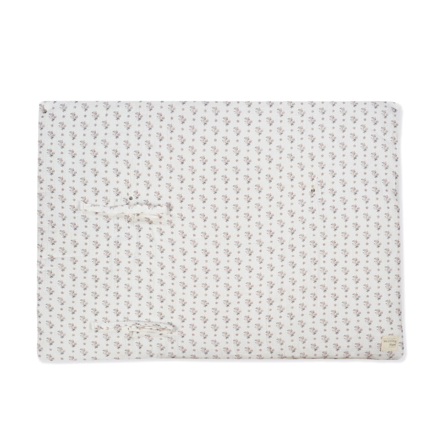 Manta branca com padrão floral e etiqueta textil