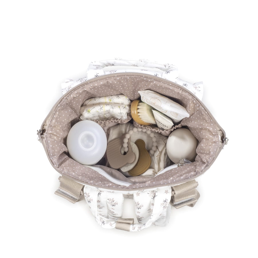 Bolsa branca com padrão floral cinza aberta cheia de acessórios para bebé em madeira e silicone