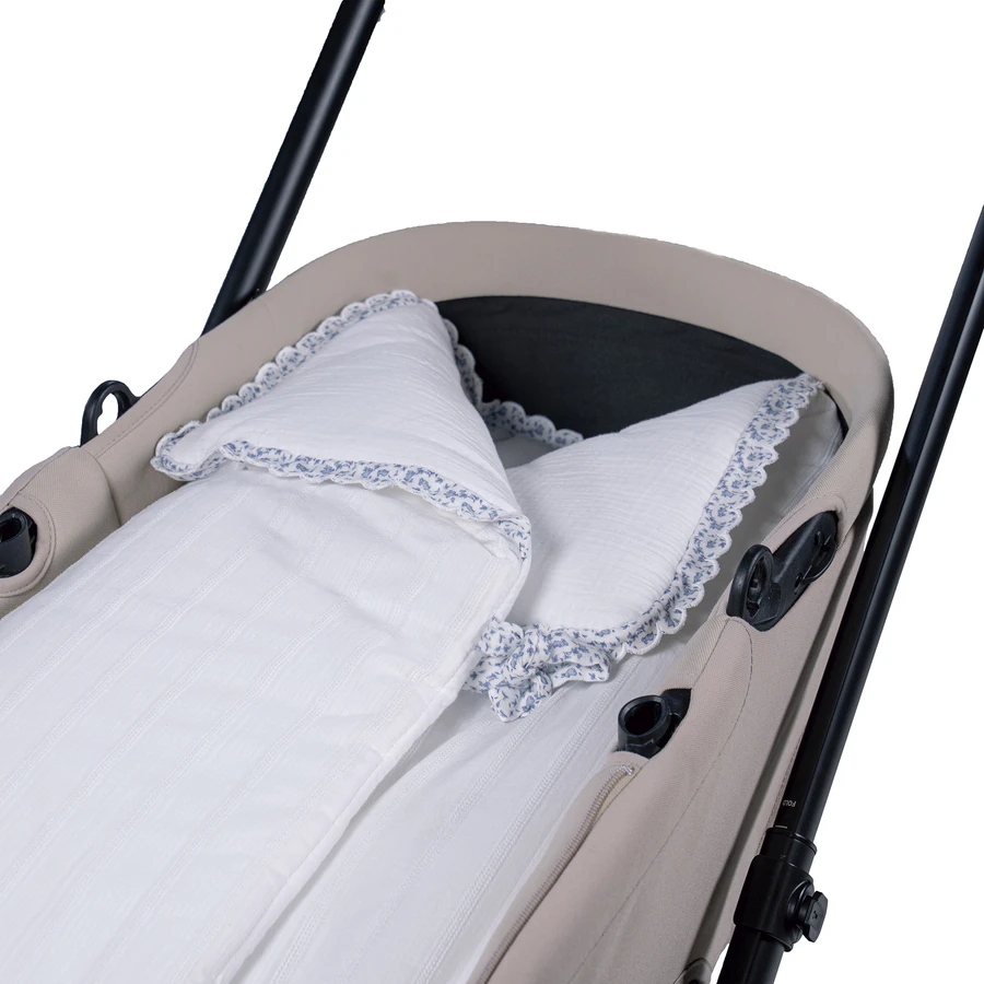 Carrinho de bebé bege com roupa de cama branca e detalhes azul claro