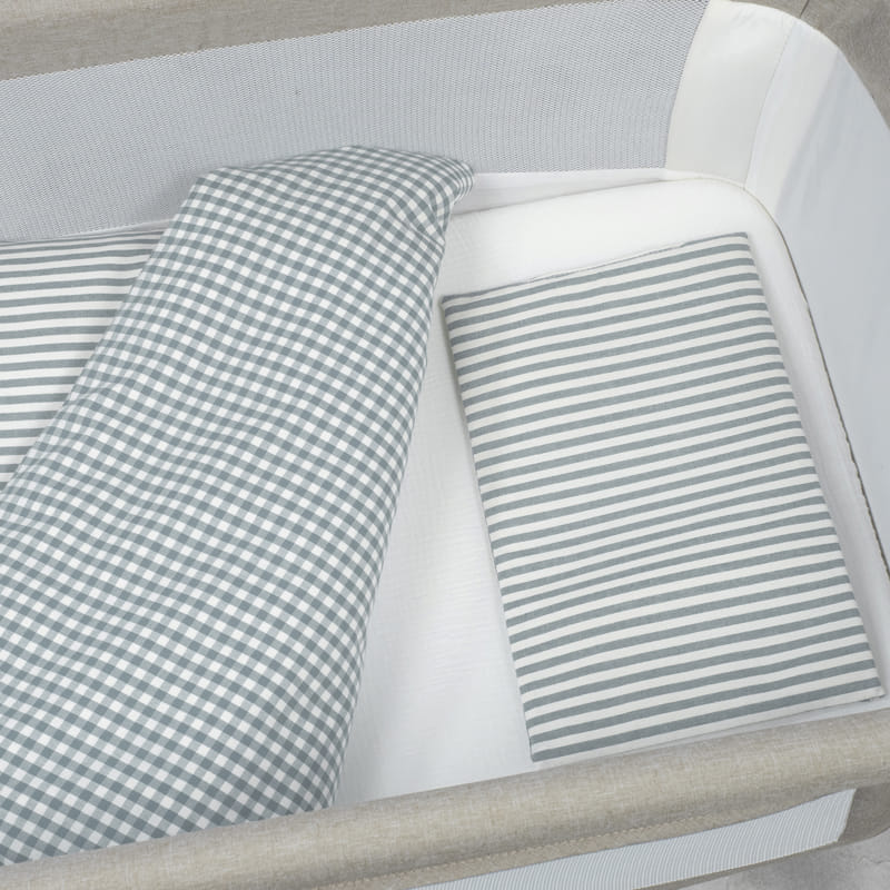 Berço com lençóis cinza e branco em padrões riscado e quadriculado