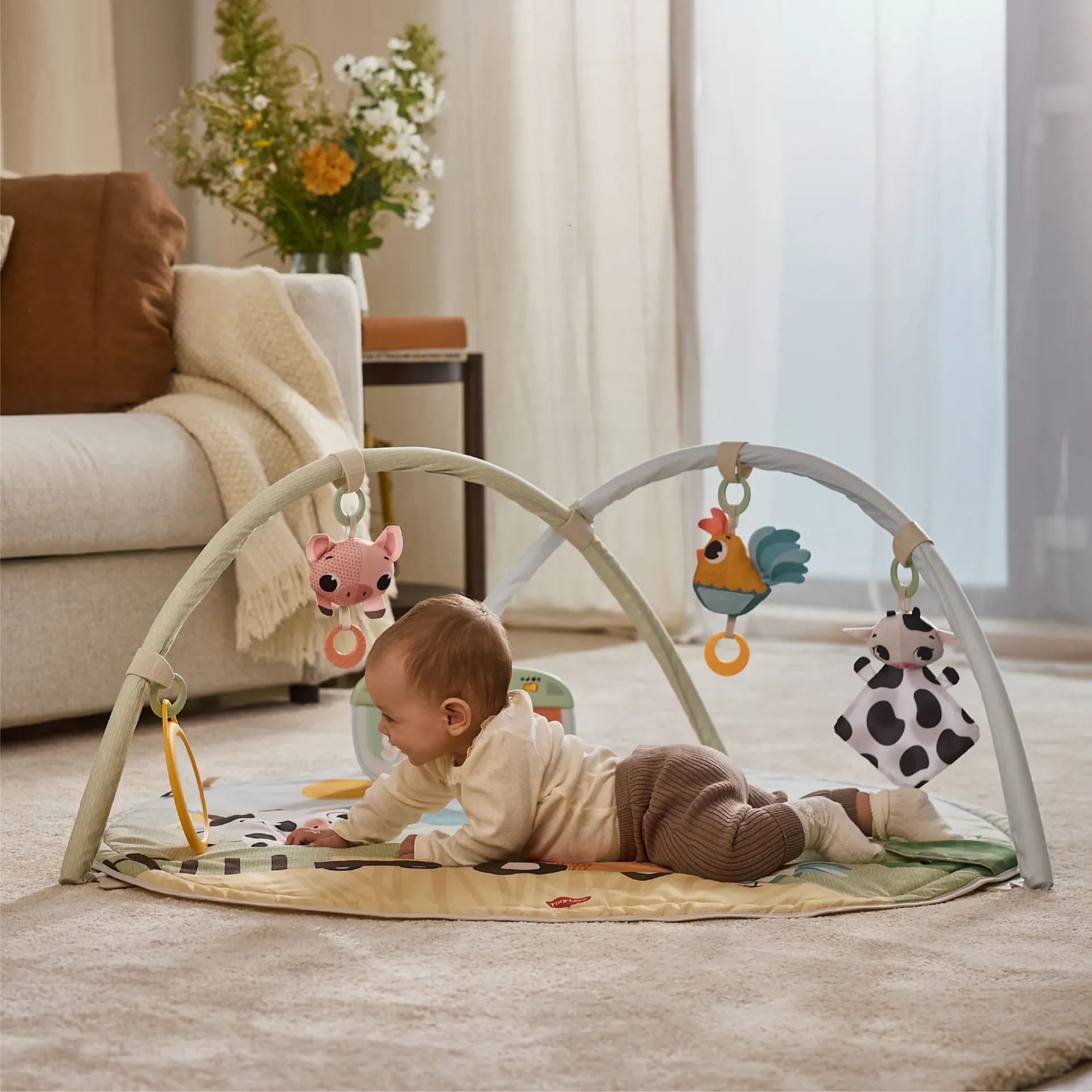 Tapete de atividades bebé com brinquedos pendurados e bebé deitado no tapete