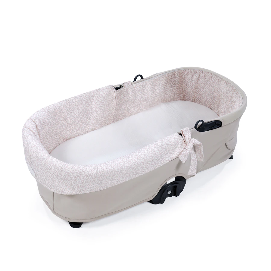 Berço portátil bege com interior floral e almofada branca