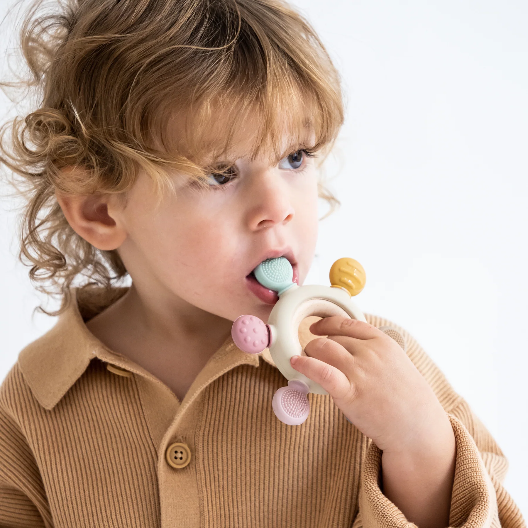 Criança a morder brinquedo de dentição colorido
