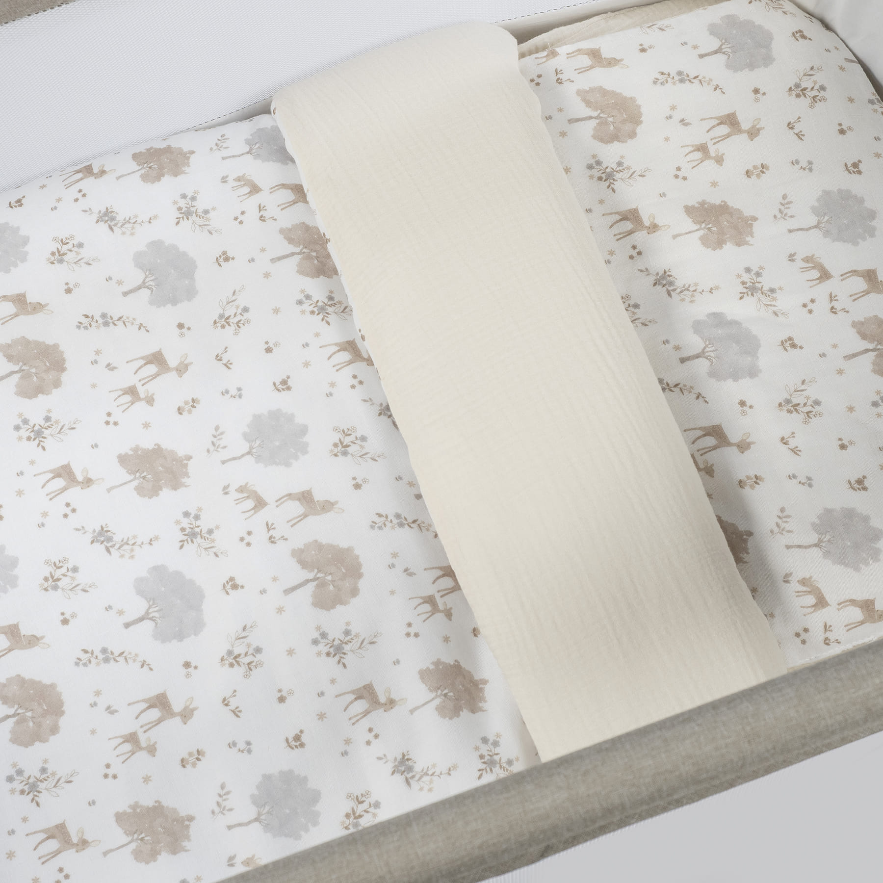 Colchão de bebé com padrão de veados e árvores e manta creme