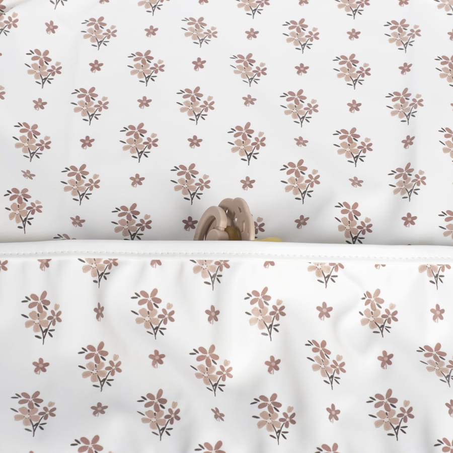 Pano branco com padrão floral e bolso com objeto rosa