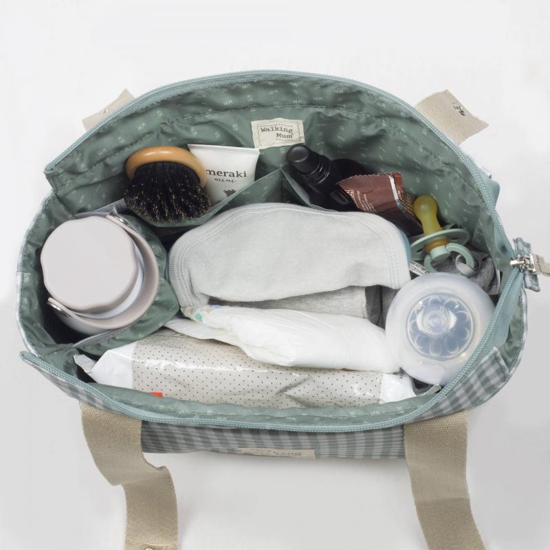 Mala de tecido verde claro aberta com itens de bebé, incluindo fraldas, chupeta e escova.