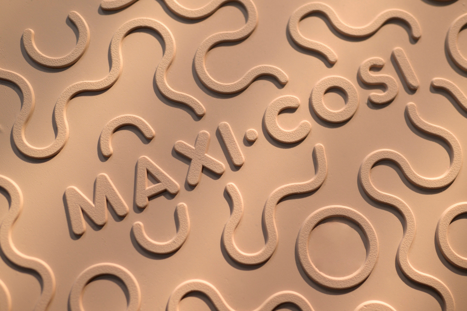 Textura em relevo com a palavra MAXI.COSI em material bege claro