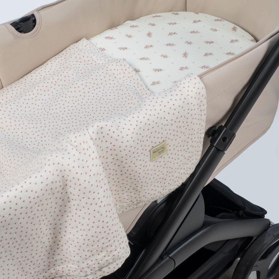 Carrinho de bebé bege e preto com almofada e manta estampadas