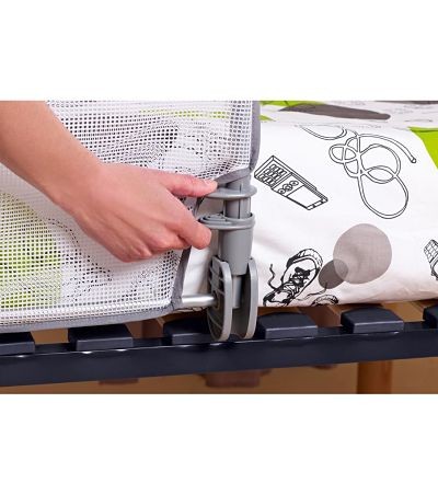 Cama de bebé com rede branca e rodas cinzentas ajustadas pela mão