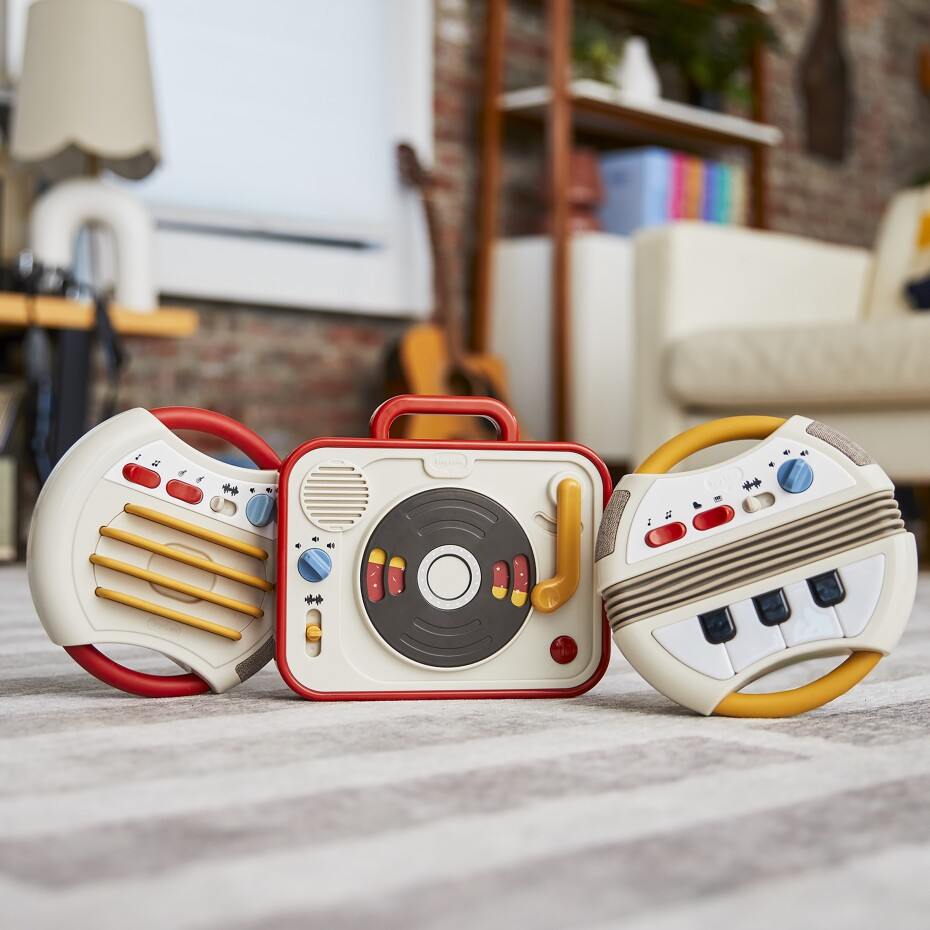 Três altifalantes portáteis branco, vermelho e amarelo num tapete em sala moderna