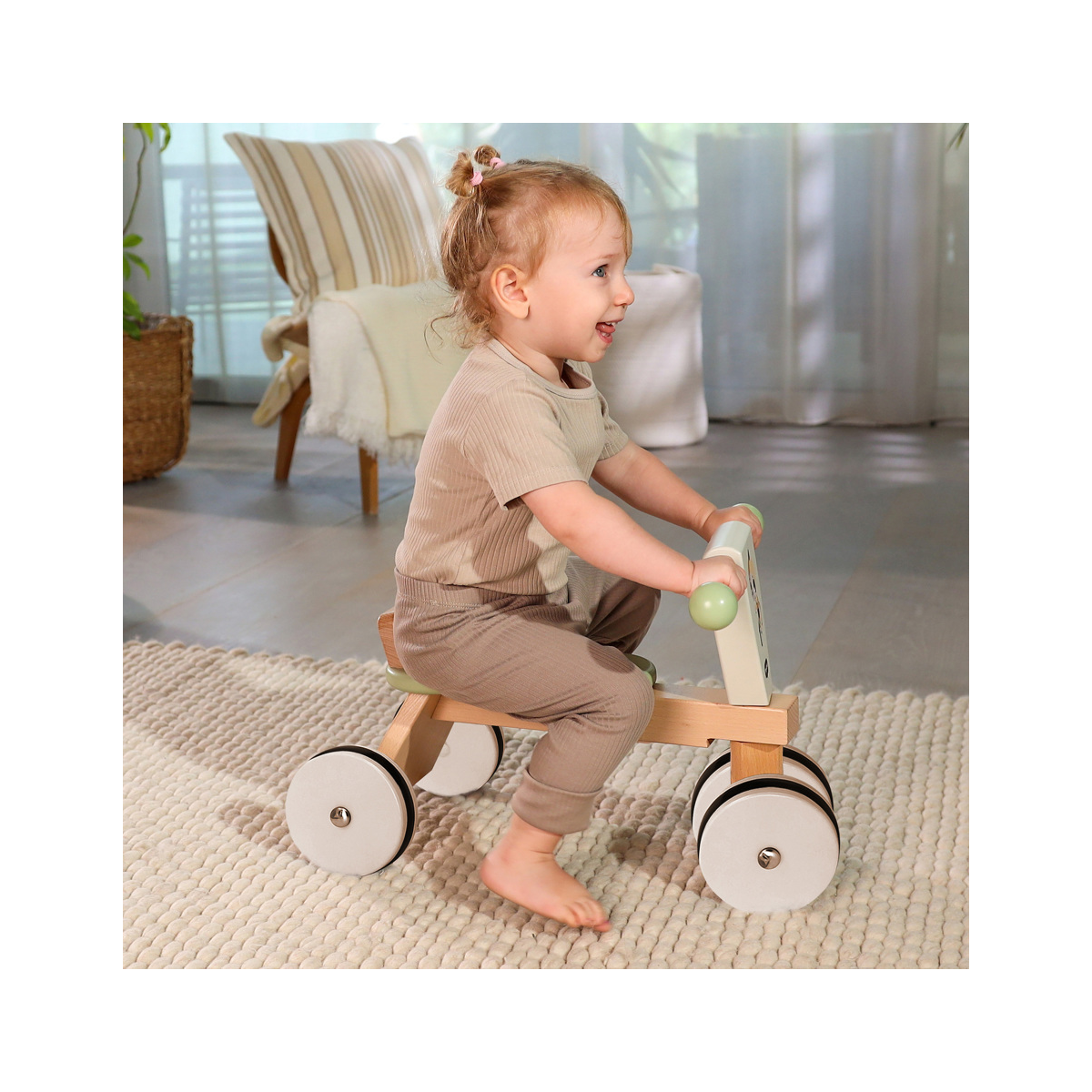 Criança brincando com carrinho de madeira sobre tapete em sala iluminada.