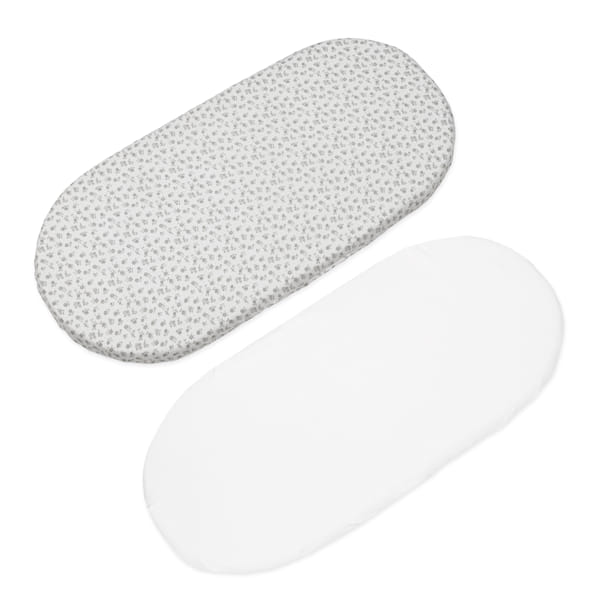 Dois protetores ovais para berço, um com padrão de folhas cinza e outro branco