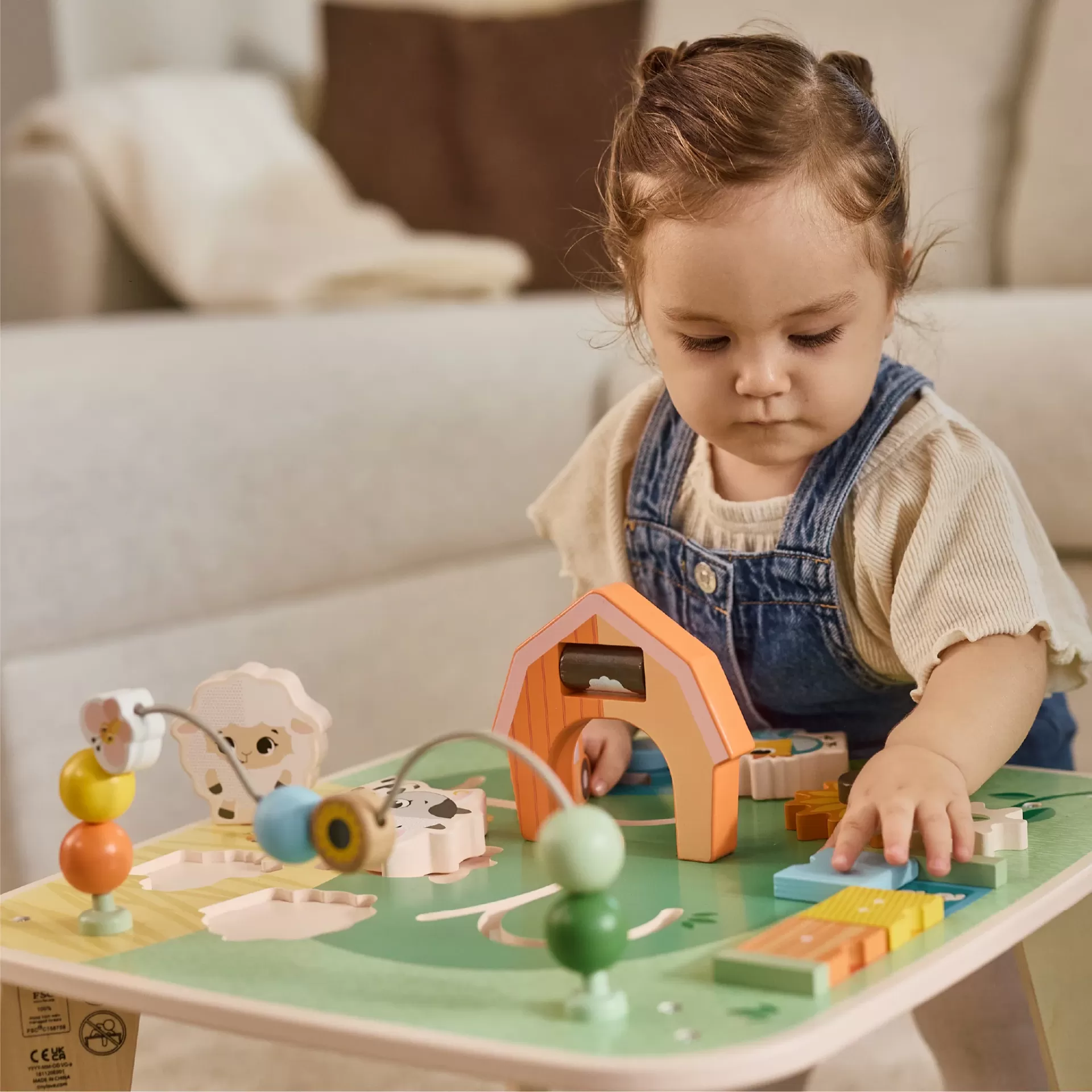 Mesa de atividades infantil em madeira com peças coloridas e criança a brincar