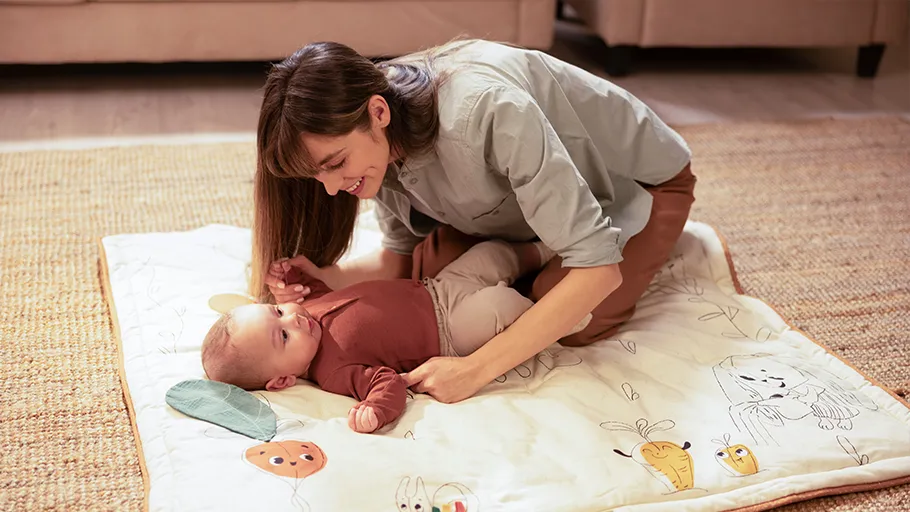Tapete de brincar para bebé colorido com desenhos de animais em ambiente interior com mãe e bebé