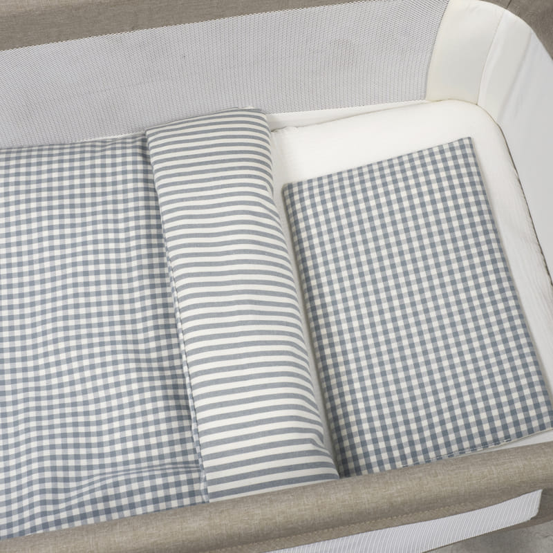 Berço com roupa de cama cinza e branca com padrão xadrez e riscas