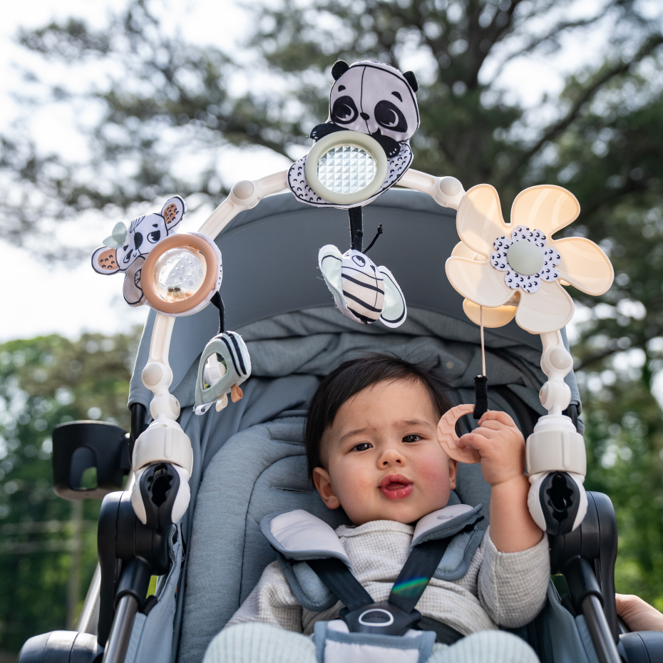 Brinquedo para bebé com peluches de panda e flor amarela pendurado numa cadeira de bebé cinzenta