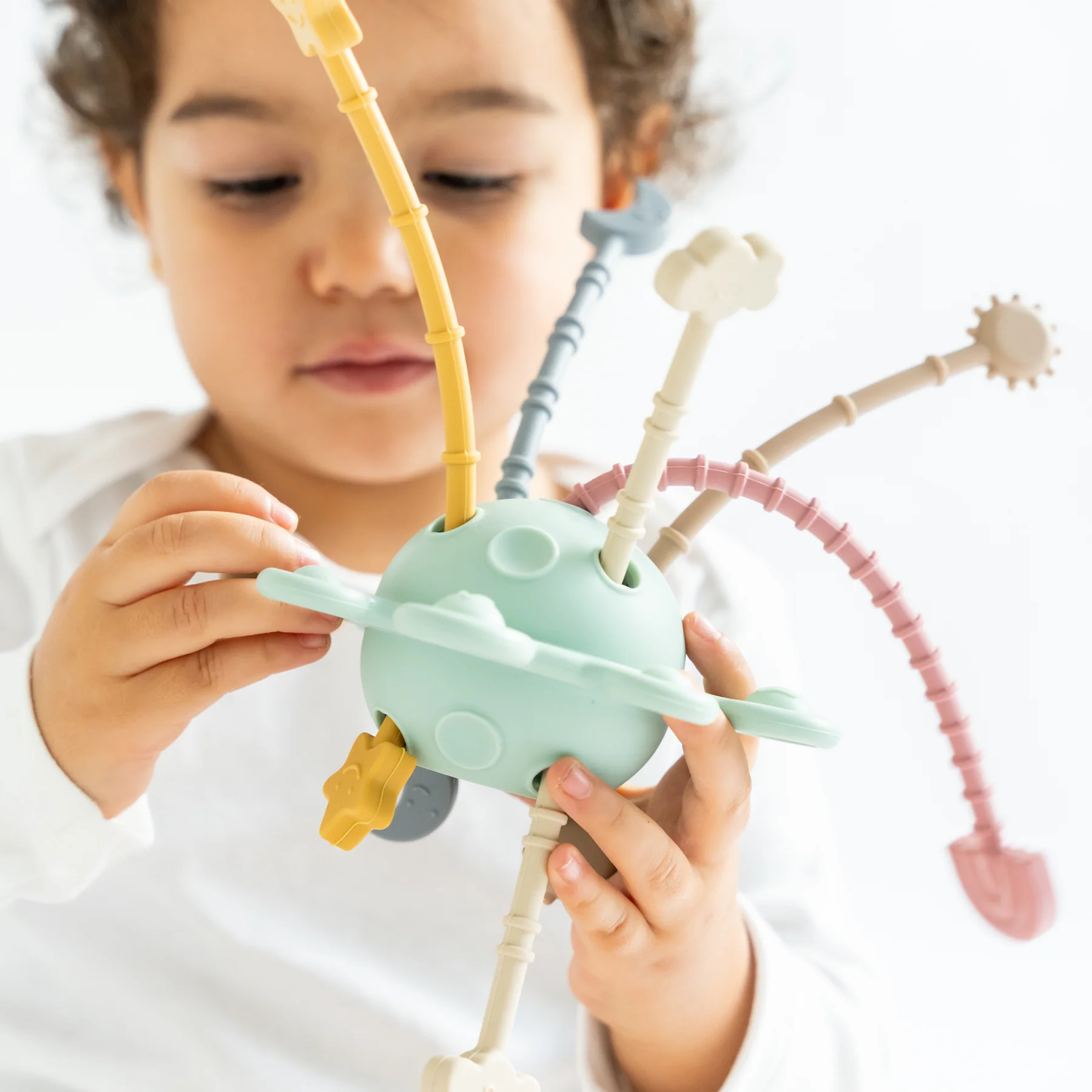 Criança a segurar brinquedo esférico com hastes flexíveis de várias cores pastel