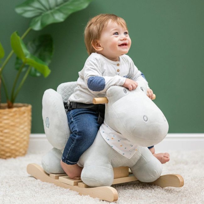 Criança a brincar num cavalo de baloiço de peluche cinzento