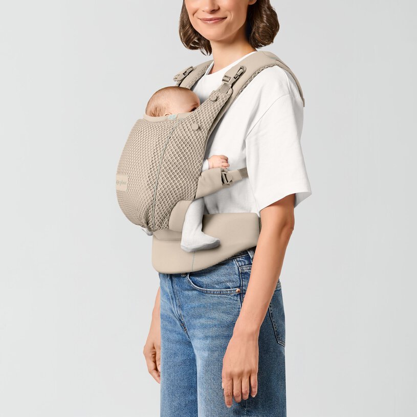 Mulher com porta-bebé bege e bebé adormecido