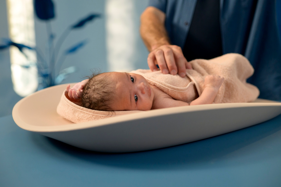 Bebé deitado numa manta cor salmão sobre balança de bebé branca