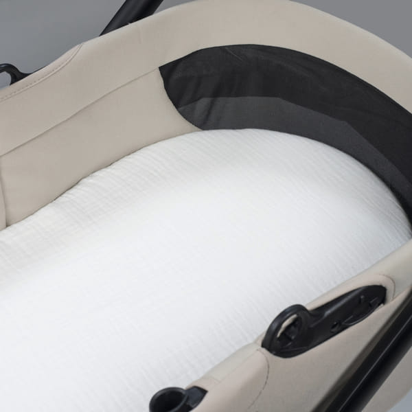 Berço portátil bege com rede preta e colchão branco