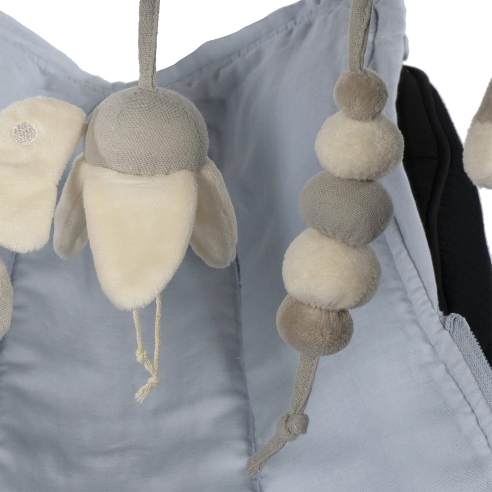 móbile de pelúcia creme e cinza pendurado em tecido azul claro