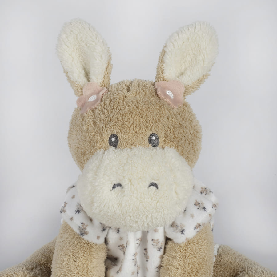 Pelúcia de animal marrom claro e bege com orelhas grandes e vestido branco com padrão floral