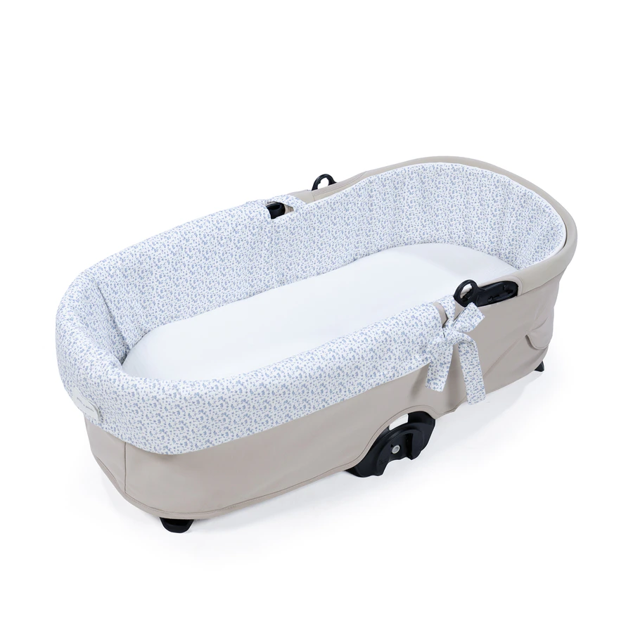 Berço portátil bege com interior em tecido branco com padrão floral azul