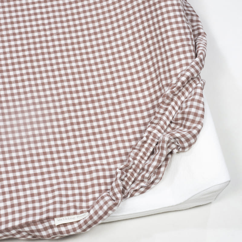 Lençol de elástico vichy branco e castanho com etiqueta Walking Mum sobre colchão branco