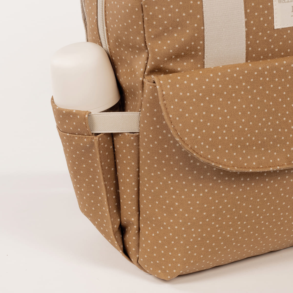 Mochila castanha com padrão de pontos brancos e bolso lateral com objeto branco