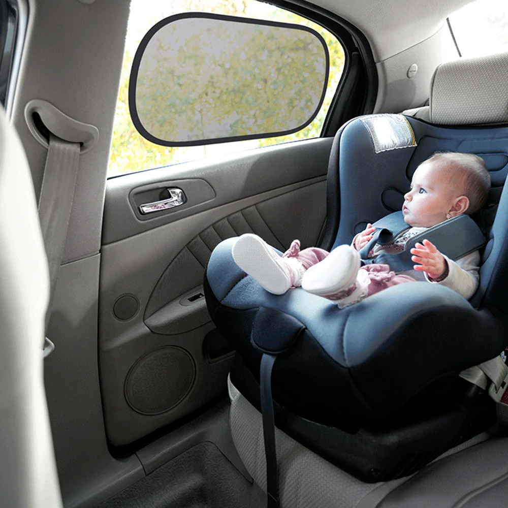Bebé numa cadeira auto azul escuro instalada no banco traseiro de um carro cinzento