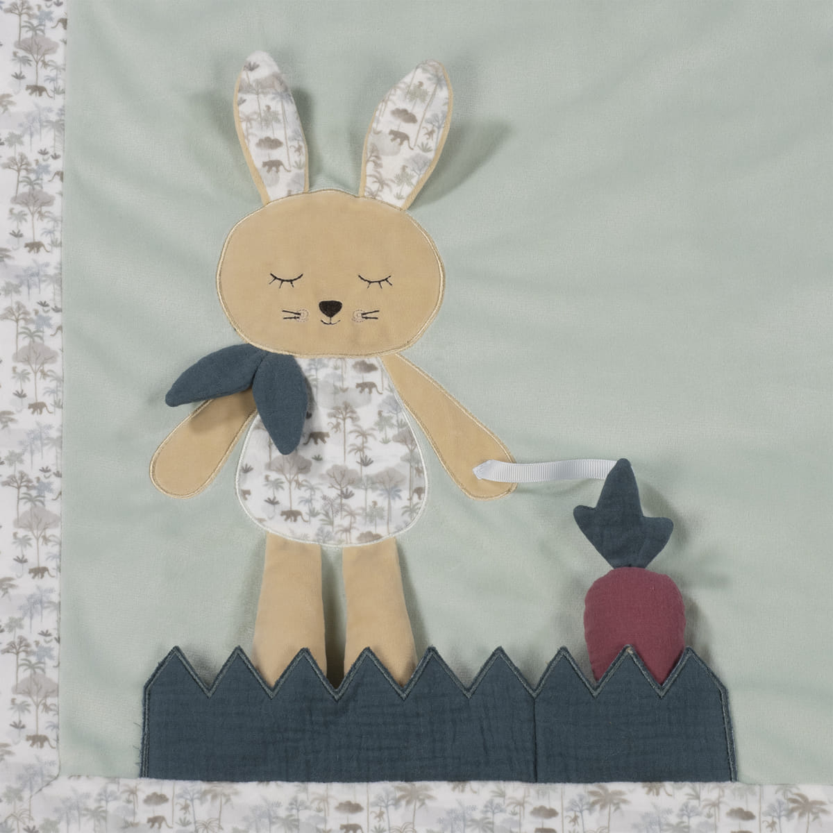 Aplicação têxtil de coelho com padrão de árvores e vegetação em tecido sobre fundo verde-água