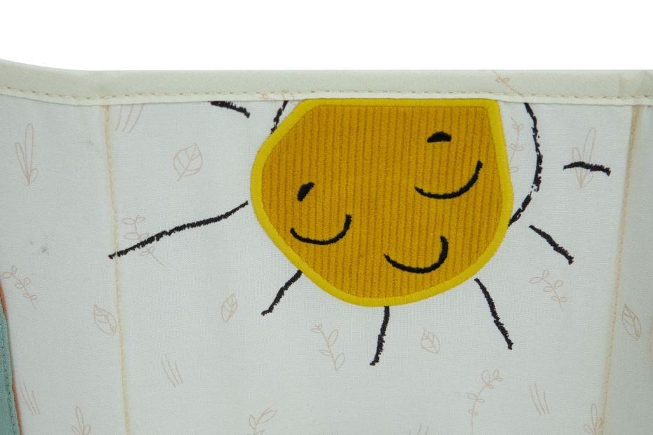 Tecido branco com desenho bordado de sol amarelo sorridente e folhas pequenas em bege