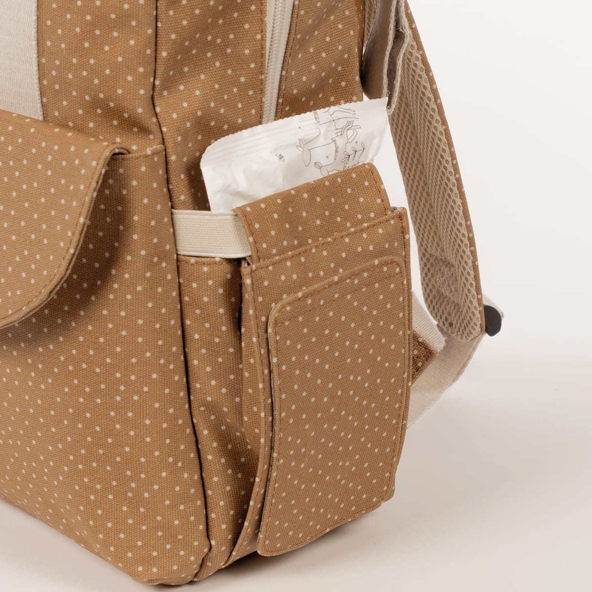 Mochila castanha com bolinhas brancas, bolso lateral com pacote branco