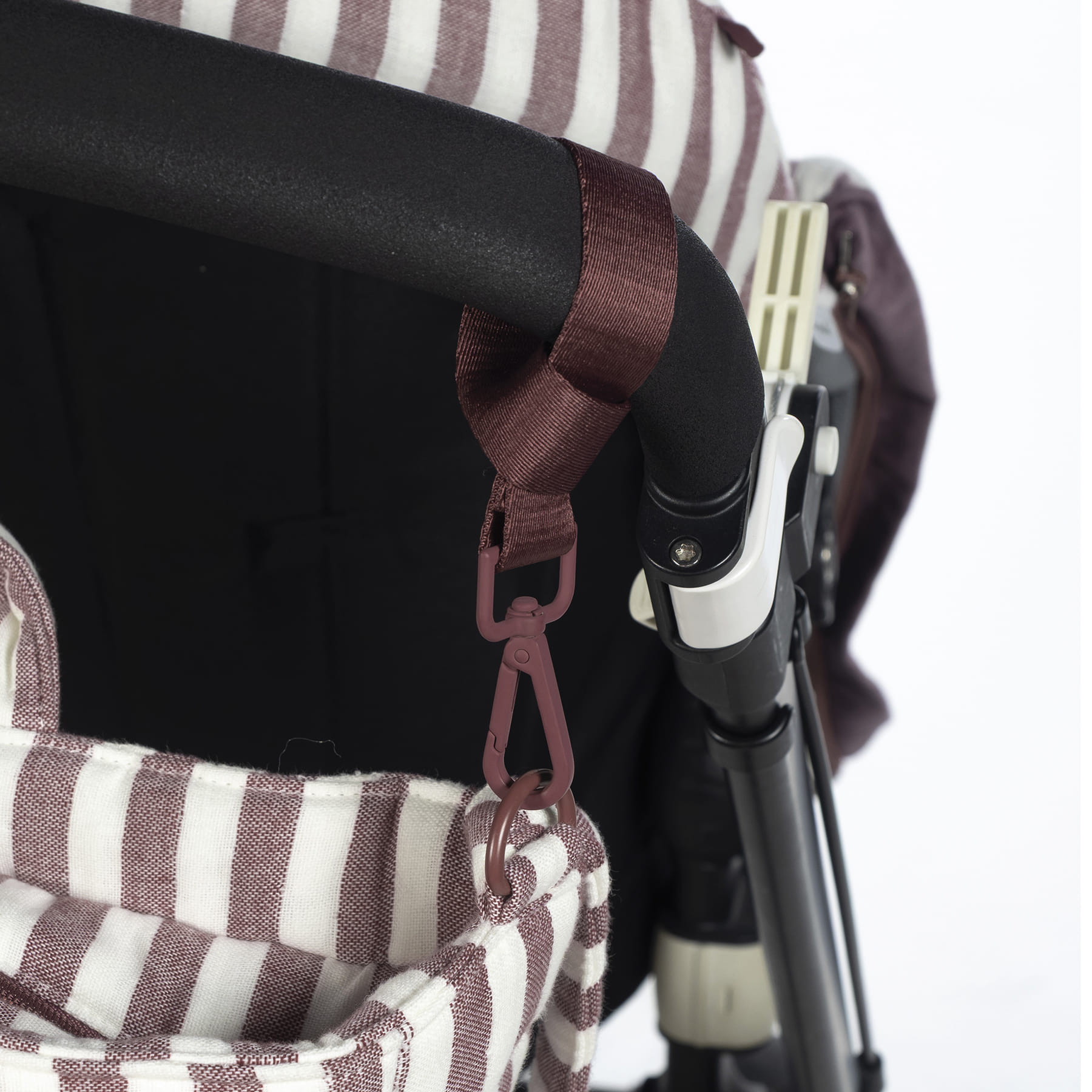 Parte de carrinho de criança com bolsa riscada branca e castanha pendurada no manípulo preto