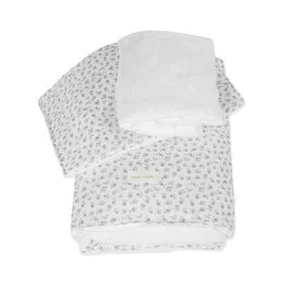 Conjunto de roupa de cama branca com padrão de flores cinzentas e pano branco dobrado por cima.