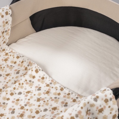 Colchão branco dentro de berço com tecido floral bege e marrom