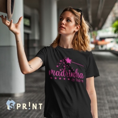 T-shirt preta com texto rosa e varinha mágica e estrelas, usada por mulher em ambiente urbano