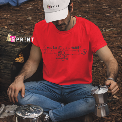 Homem com t-shirt vermelha e boné branco sentado no chão da floresta com utensílios de campismo.