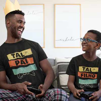 Pai e filho sorridentes sentados no sofá usando t-shirts pretas combinando a jogar videojogos.