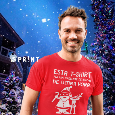 Homem com t-shirt vermelha com texto e ilustração de Natal, árvore e prédio ao fundo