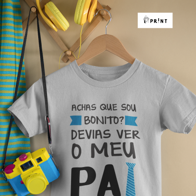 Camisola cinza de criança com texto em português, auscultadores amarelos, casaco às riscas azuis e verdes e câmara de brincar azul e amarela