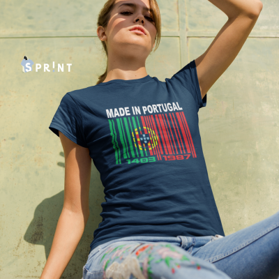 Mulher usando t-shirt azul escura 'MADE IN PORTUGAL' com código de barras colorido, sentada com jeans estampados