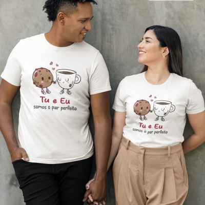 Casal com t-shirts brancas ilustradas com bolacha e chá e texto romântico em português, posando em fundo cinzento.