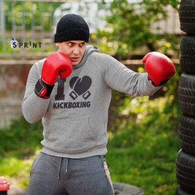 Pessoa a usar roupa de treino cinzenta e luvas vermelhas a praticar boxe ao ar livre