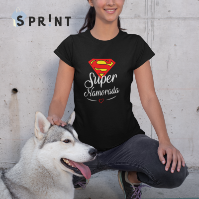Mulher com t-shirt preta 'Super Namorada' e cão husky sentado junto a parede de cimento