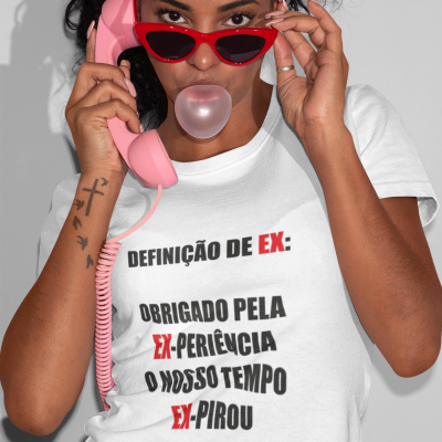 Mulher com camisa branca com texto em português, óculos de sol vermelhos, telemóvel rosa e pastilha elástica