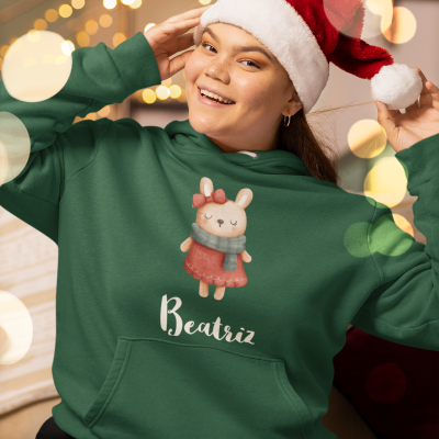 Sweatshirt verde com estampa de coelho e nome Beatriz, usado com gorro de Natal num ambiente festivo
