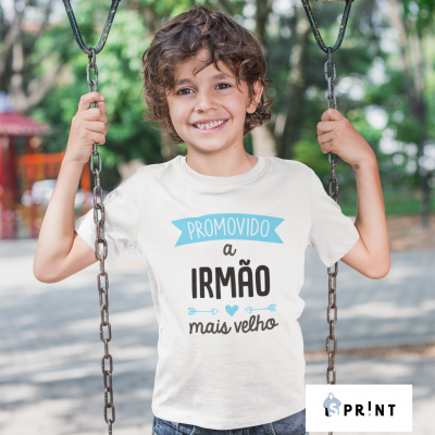 Criança com camiseta branca ao ar livre num parque, segurando correntes de baloiço.